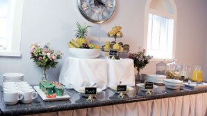 Un buffet de petit-déjeuner avec des présentoirs de nourriture clairement identifiés, proposant notamment du « muesli », du « maïs », de l’« armoise », des « fruits » et du « blé ».