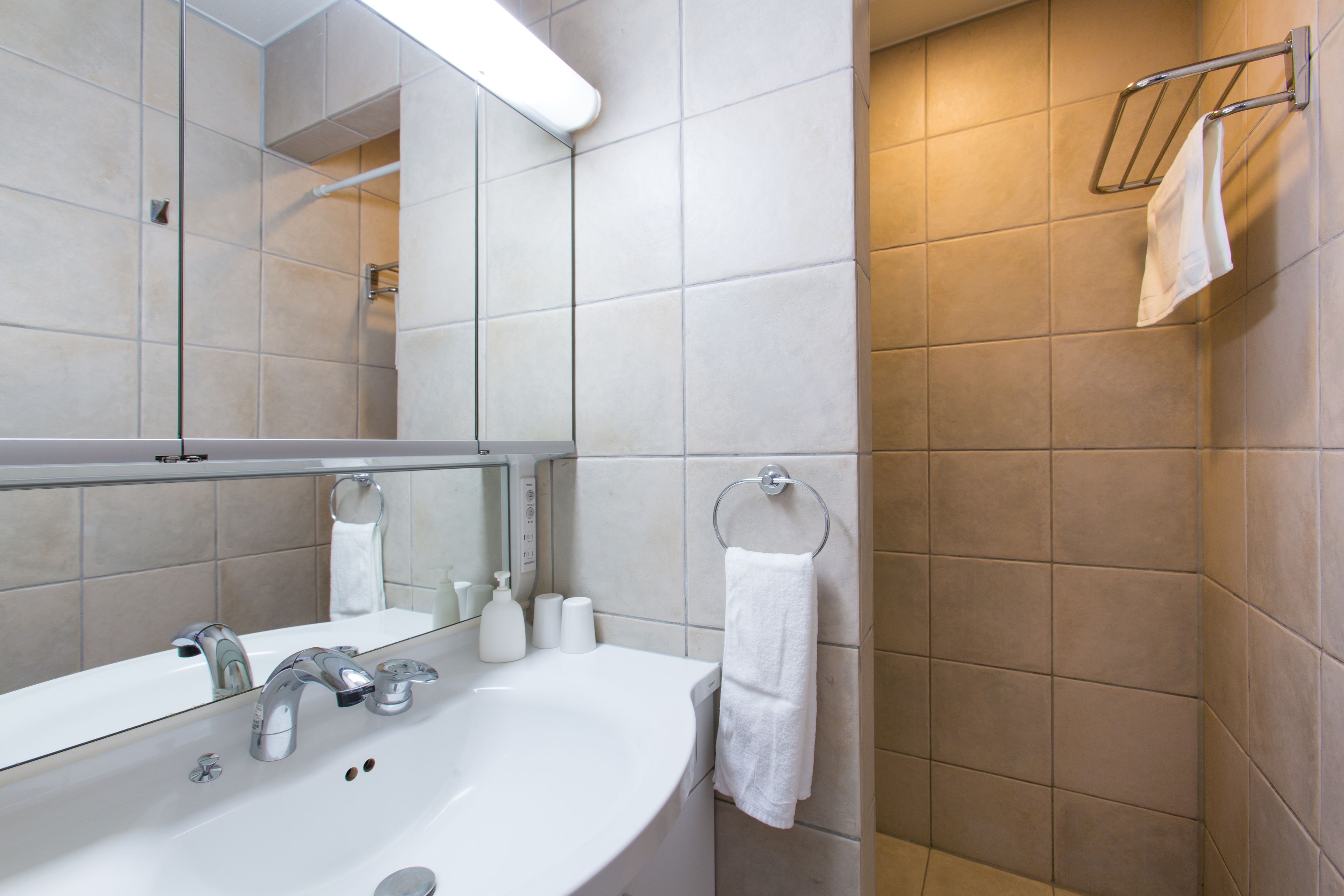 Un baño moderno con un lavamanos amplio, espejo y barra para toallas.