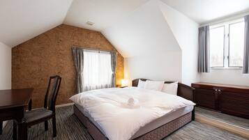 A hotel room with a large bed, a desk, a chair, a window with curtains, and a wooden wall.