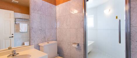 Een moderne badkamer met een wastafel, toilet en douchecabine met glazen wanden.