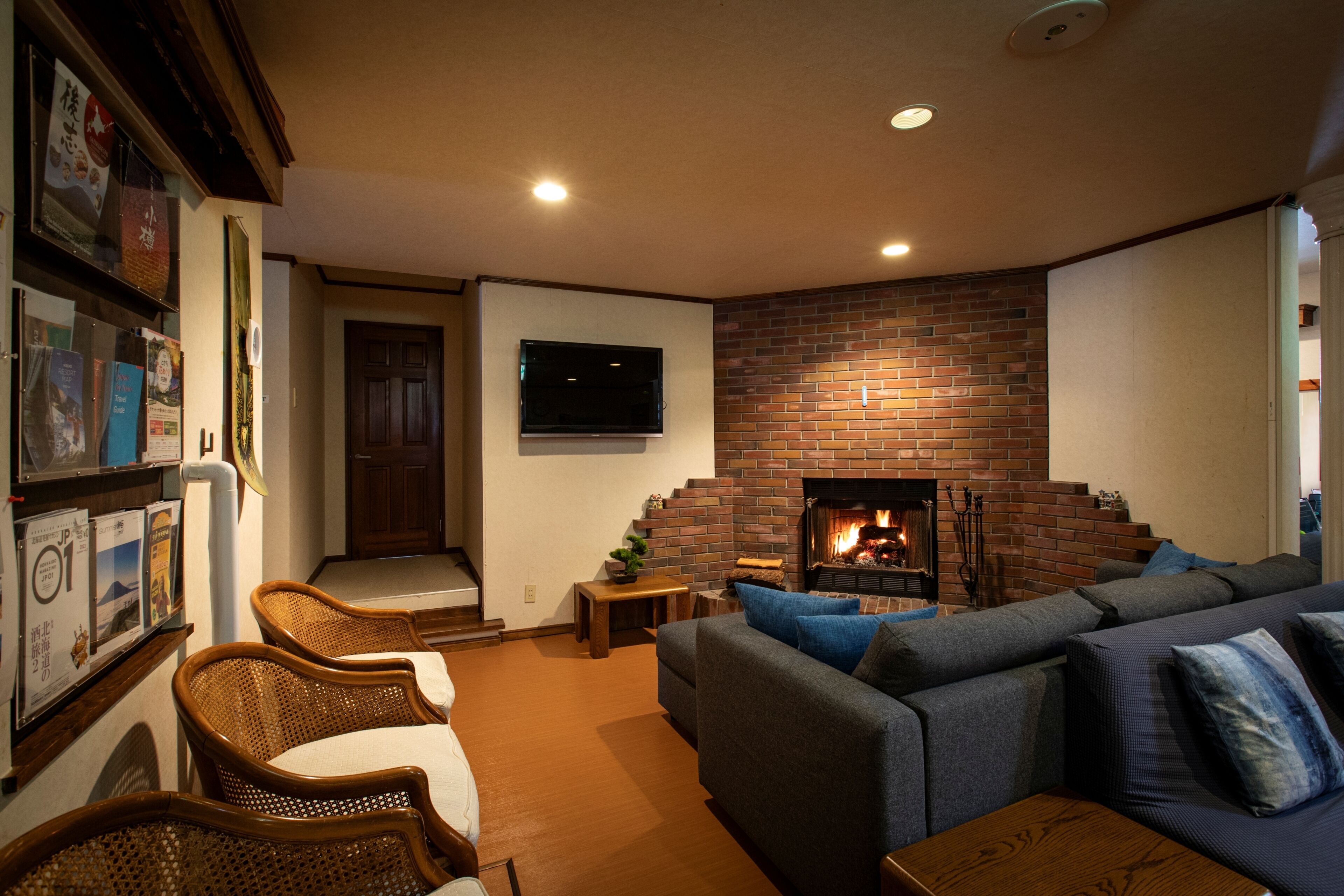 A living room with a brick fireplace, a television mounted on the wall, and a sofa with cushions.