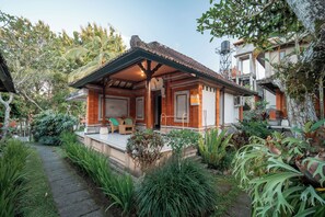 Ein Haus mit einem Ziegeldach, einer Veranda mit einer Bank und einem Garten mit verschiedenen Pflanzen.