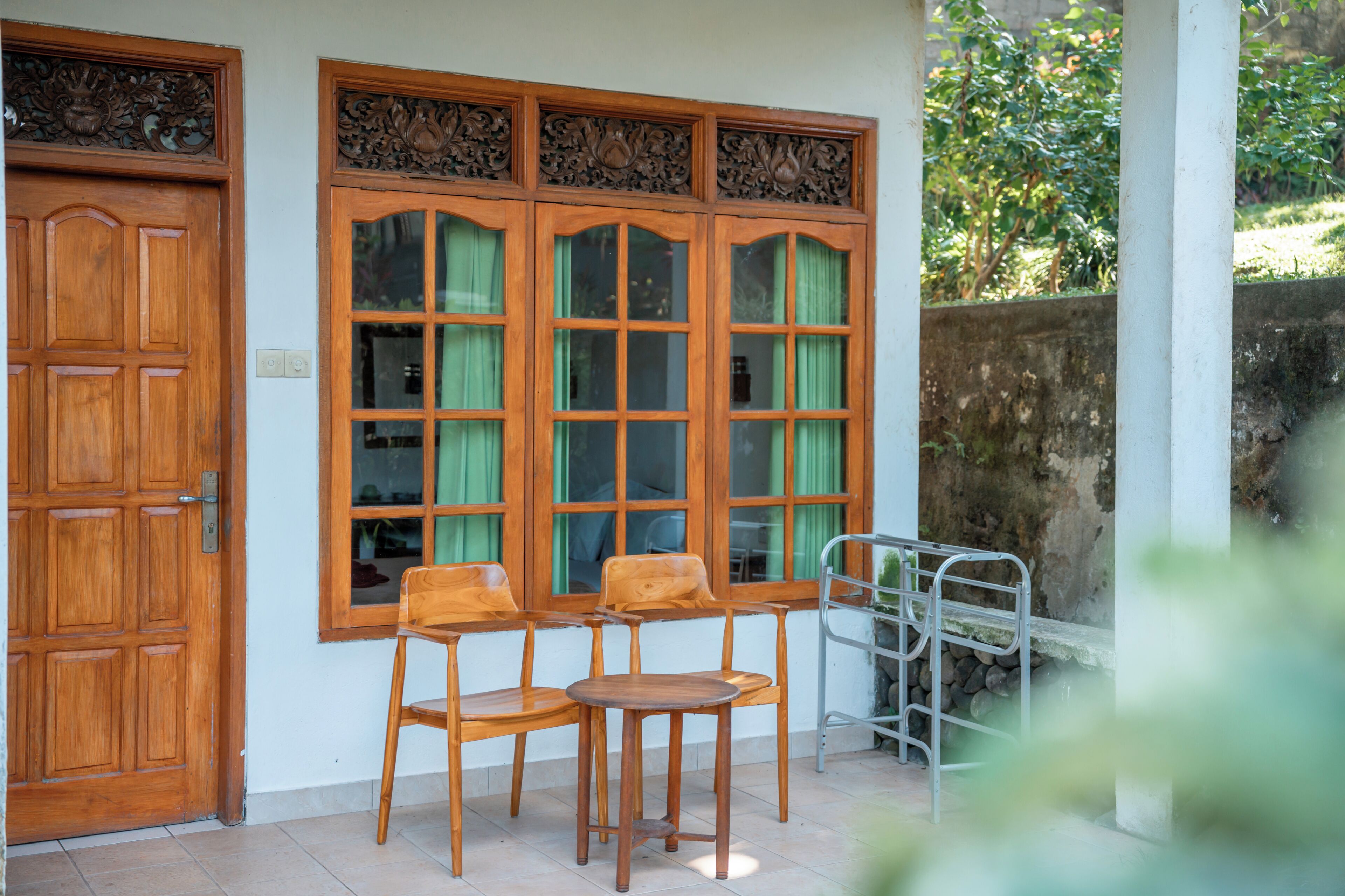 Una puerta de madera, una ventana con cortinas, y un juego de sillas y mesas de madera.