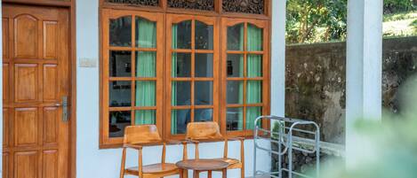 Una puerta de madera, una ventana con cortinas, y un juego de sillas y mesas de madera.