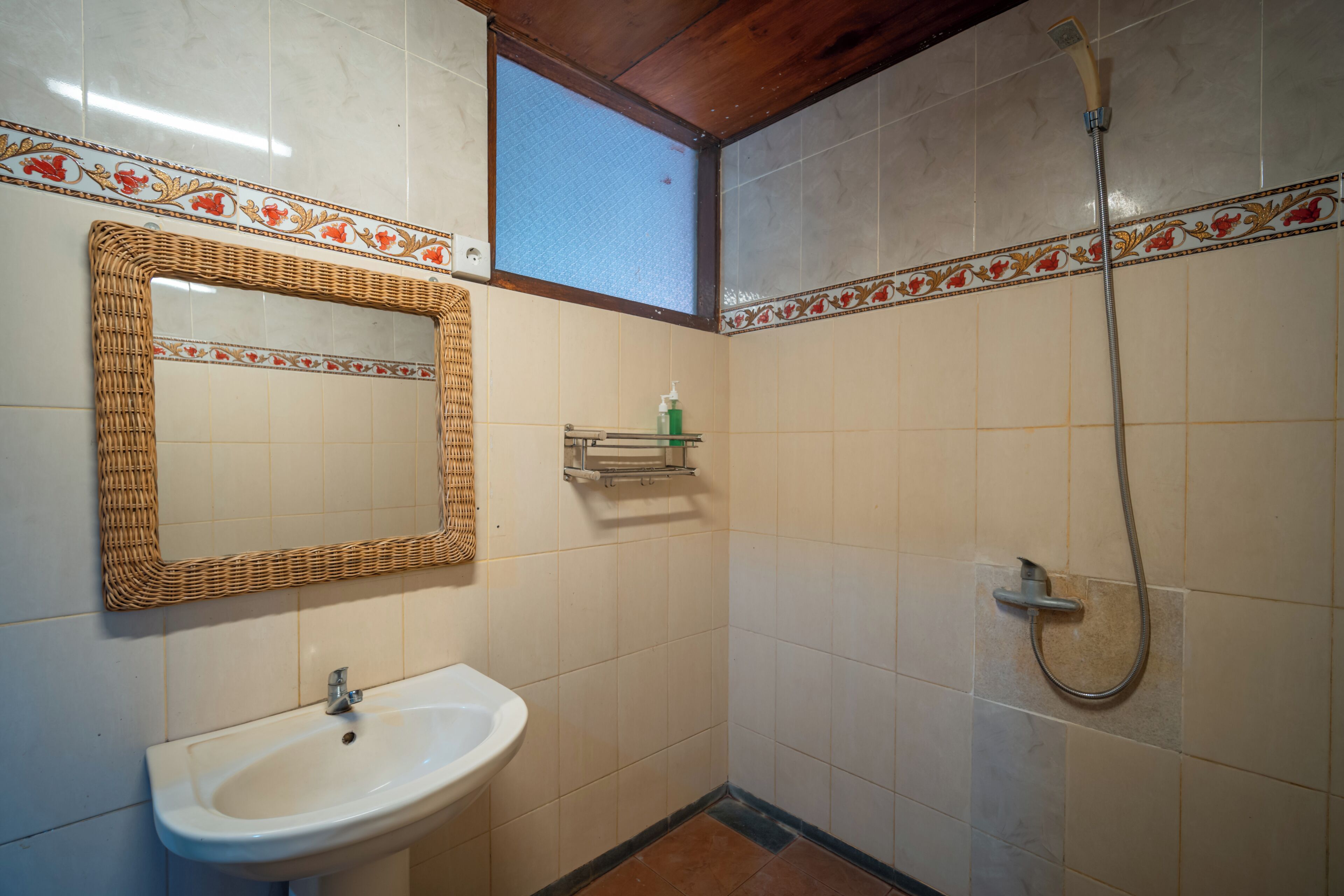 A bathroom with a sink, mirror, shower, and decorative tiles.