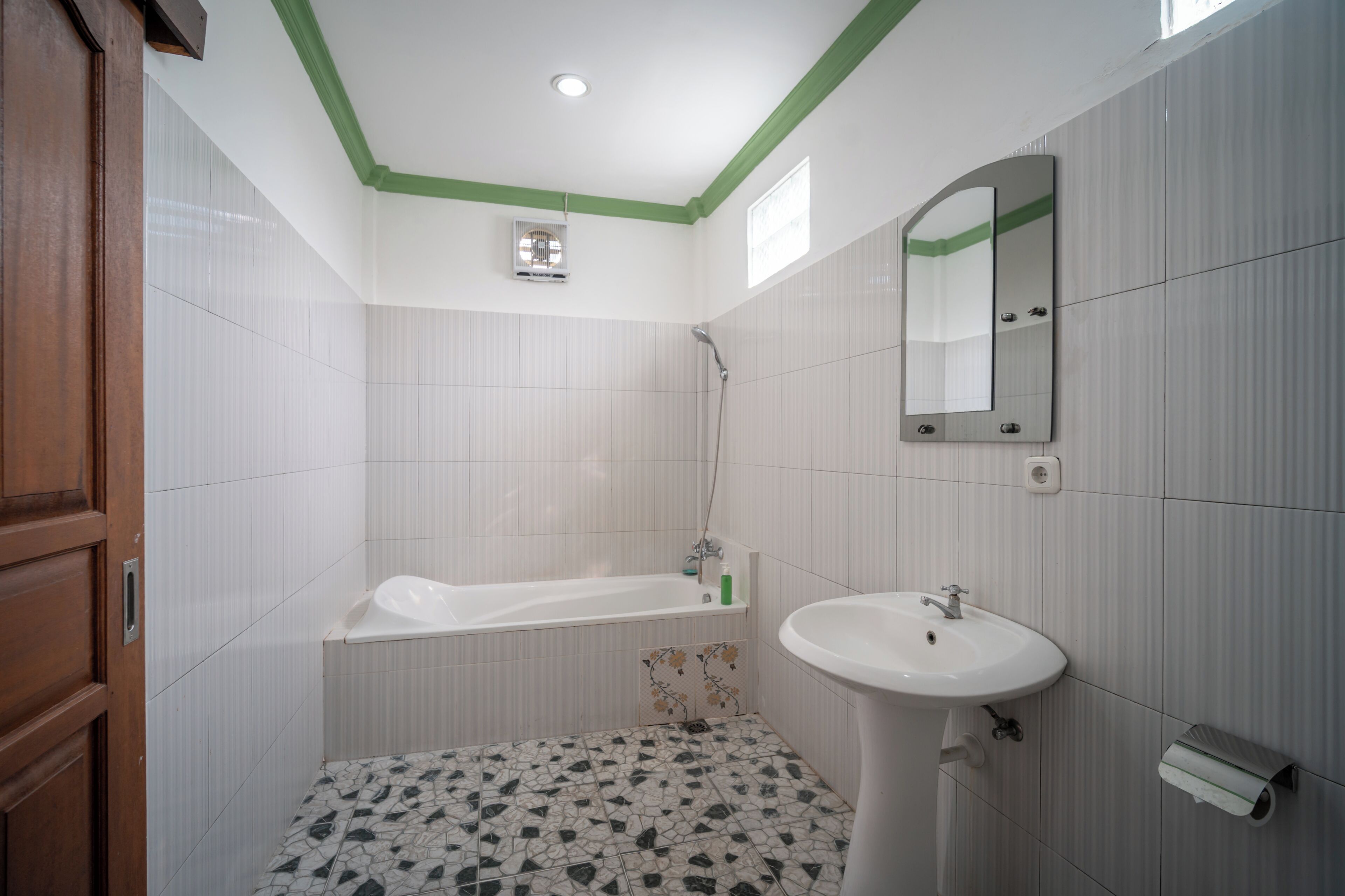 A bathroom with a bathtub, sink, mirror, and green-painted ceiling.