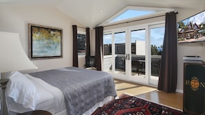 A bedroom with a bed, a desk, a chair, a large window, and a sliding glass door leading to a balcony. - Perfect Laguna Beach Vacation-ocean views/beach across street/town 1 block (Laguna Beach)