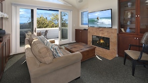 A living room with a sofa, a coffee table, a fireplace, a television, and a view of the ocean through large sliding glass doors. - Perfect Laguna Beach Vacation-ocean views/beach across street/town 1 block (Laguna Beach)