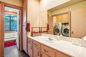 Bathroom features a vanity with a sink, modern faucet, and wooden cabinets with metal handles.