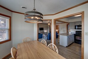 A dining area with a wooden table and chairs, a kitchen with a microwave and stove, and a ceiling fan.