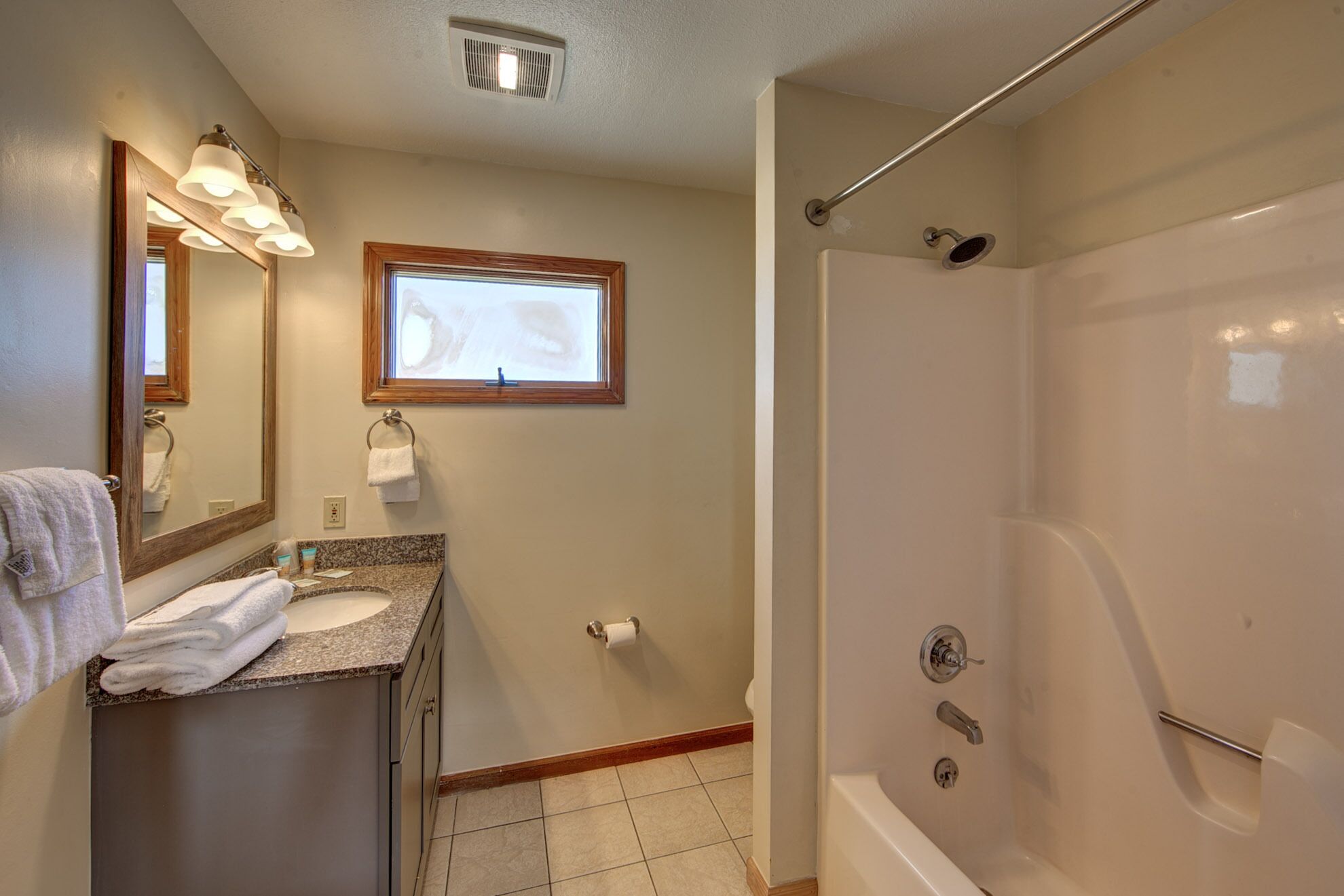 A bathroom with a sink, mirror, towel rack, and a walk-in shower.