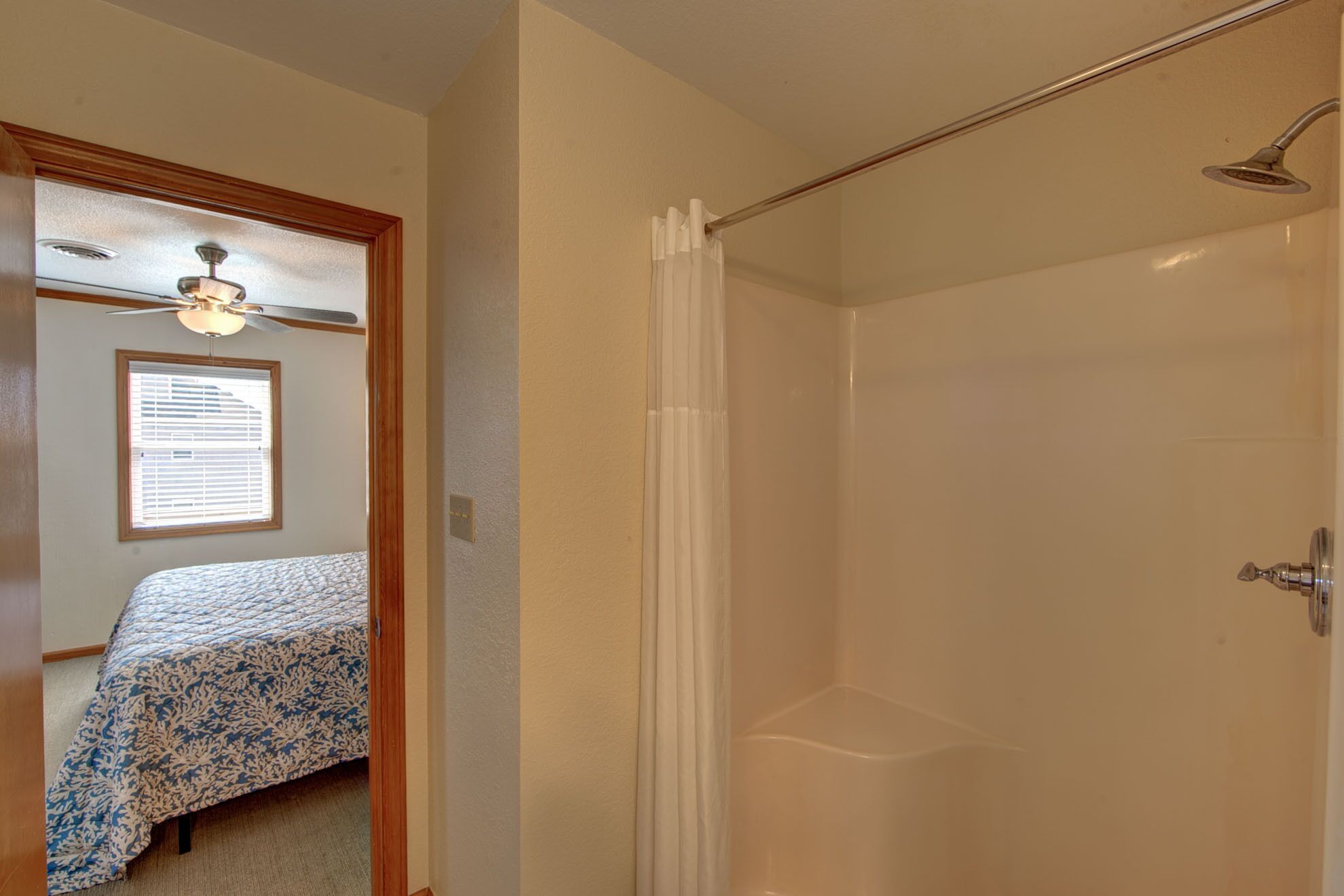 Une chambre à coucher avec un lit, un ventilateur de plafond et une fenêtre avec des stores.