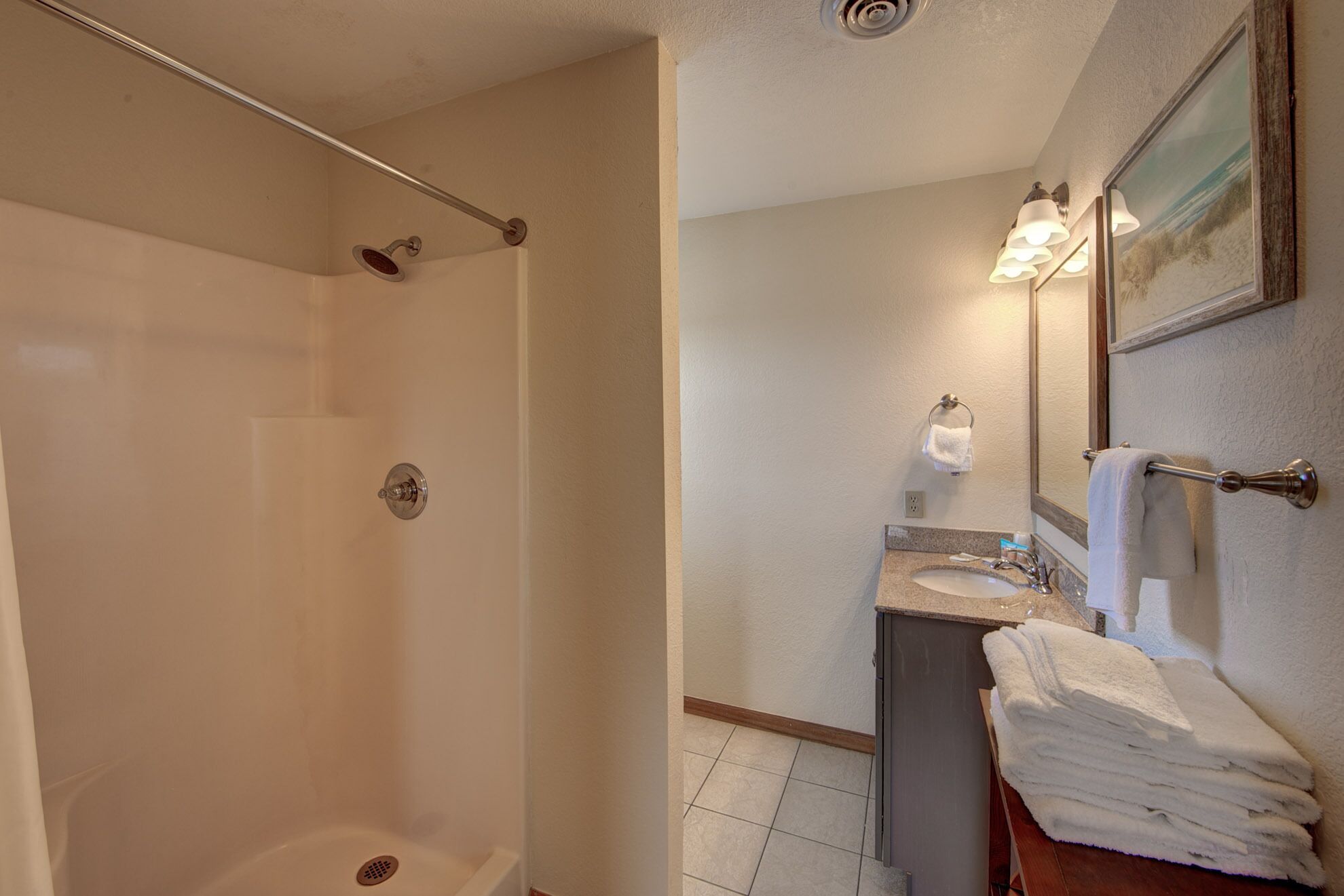 Une salle de bain avec une douche, un lavabo et un miroir.
