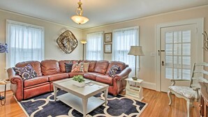 A living room with a brown leather sofa, a white coffee table, and a patterned rug. - Central Wadesboro Home: Walk to Downtown Shops! (Wadesboro)