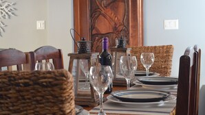 Een eettafel gedekt met borden, glazen en een fles.