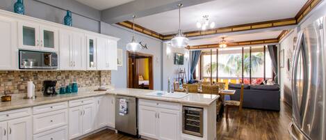 A modern kitchen with white cabinets, a built-in oven, and a large refrigerator.