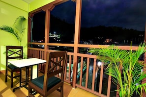 A balcony with a table and chairs, overlooking a cityscape at night.