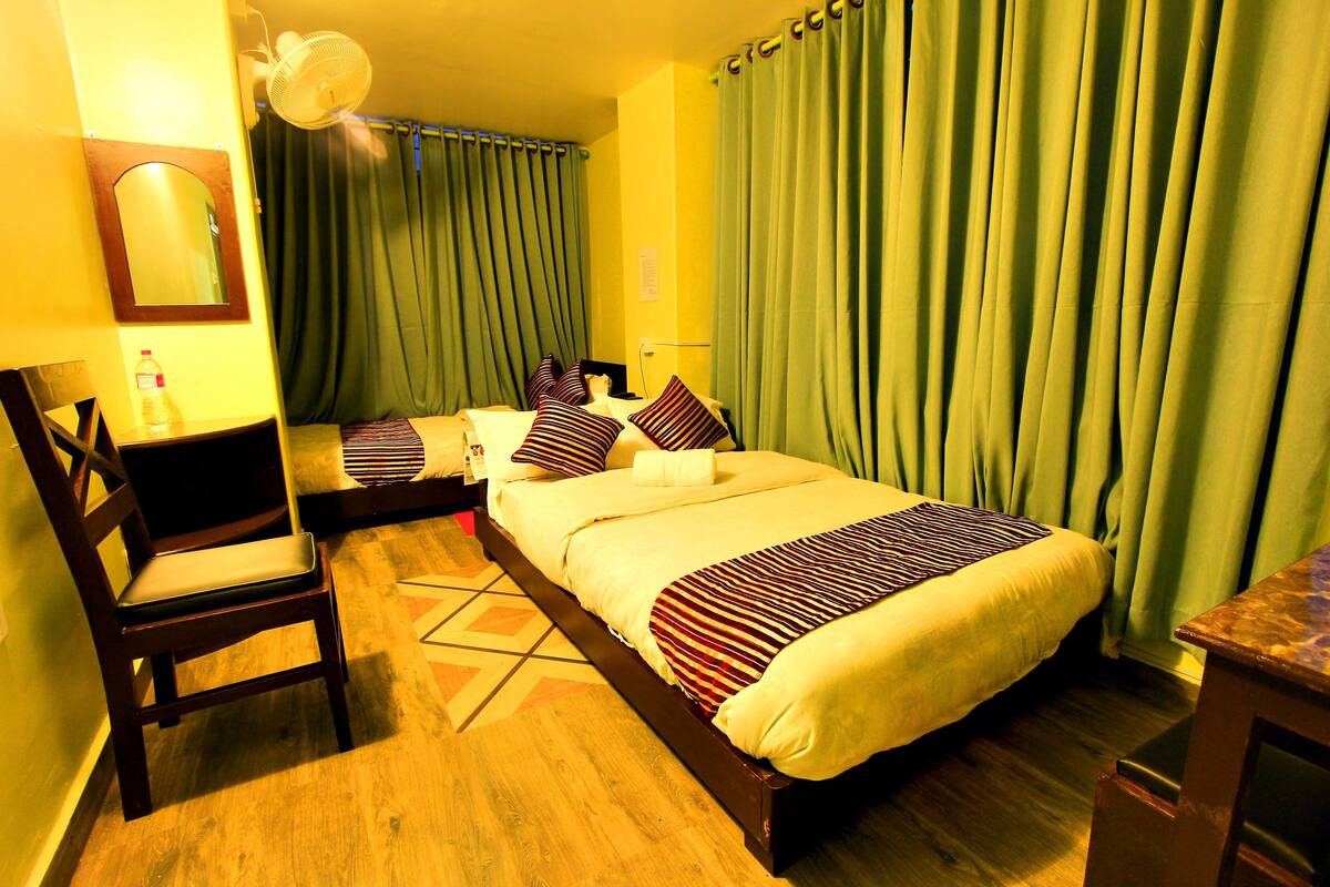 A hotel room with two beds, a chair, a desk, and a mirror.