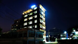 A multi-story building with illuminated windows and a sign indicating a hotel. - Hotel Arhant Inn (Pokhara)
