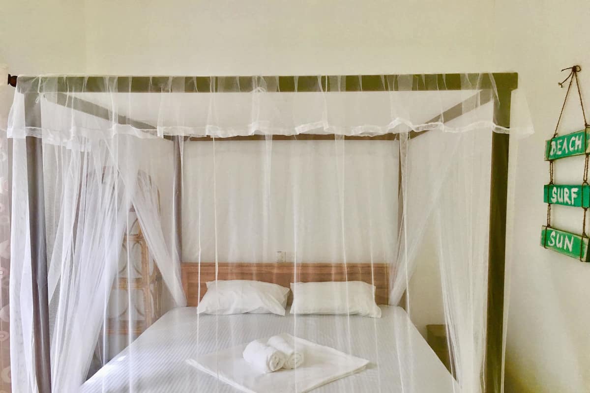 A bed with a canopy, pillows, and a rolled towel.