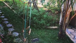 A dreamcatcher hanging in a lush garden with a stone pathway and palm trees. - Villa Coconut - Hostel (Weligama)