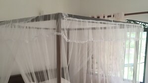 A four-poster bed with a white canopy, a wooden headboard, and a white mattress. - Villa Coconut - Hostel (Weligama)