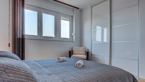Ein Schlafzimmer mit einem großen Bett, einem Sessel und einer Schiebetür.