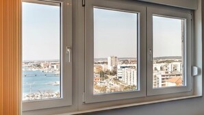 Ein Fenster mit drei Fenstern, das Blick auf eine Stadtlandschaft mit Gebäuden und einem Wasserlauf bietet.