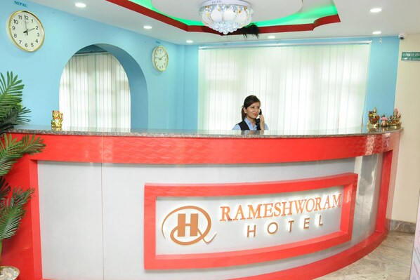Una recepción en el Hotel Rameshworam con un reloj, una recepcionista y una araña.