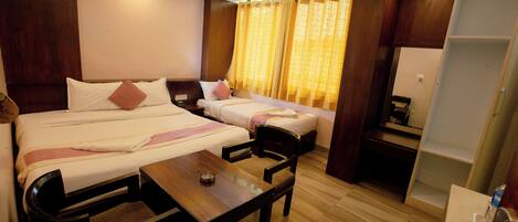 A hotel room with two beds, a small table, a chair, a desk, and a wardrobe.
