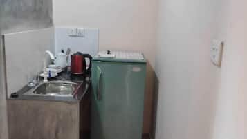 A compact kitchen with a sink, a small refrigerator, and a tiled floor.