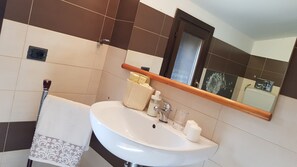 Une salle de bain avec un lavabo blanc, un miroir et un porte-serviettes.