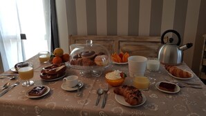 A breakfast table with pastries, fruits, and beverages, set against a striped wall. - Barolo houses with large terrace and swimming pool for the whole family (SIRACUSA)