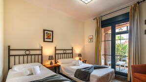 Ett hotellrum med två sängar, en balkong med ett bord och stolar samt utsikt över omgivningen.
