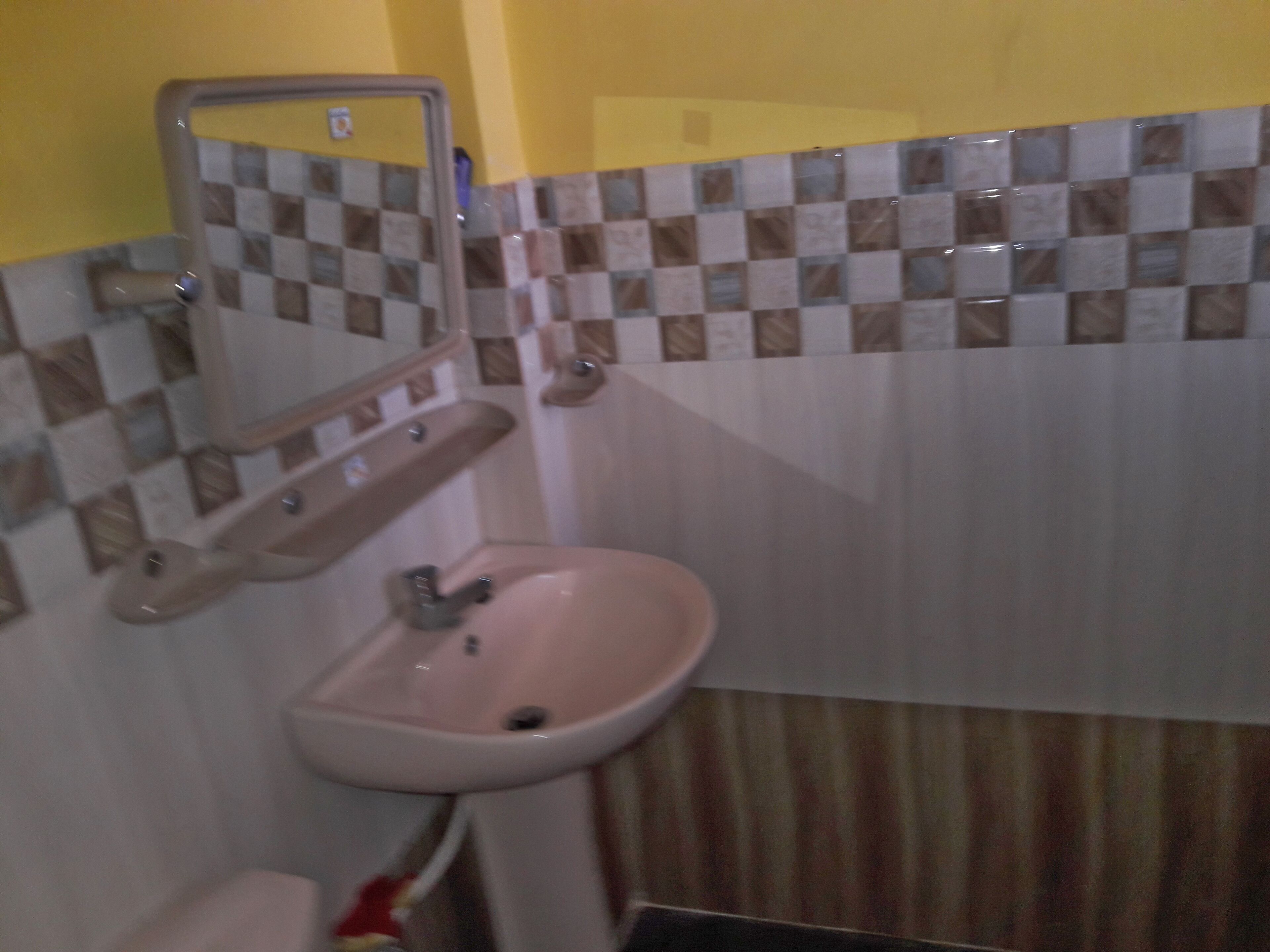 Een badkamer met een wastafel, spiegel en betegelde muren.
