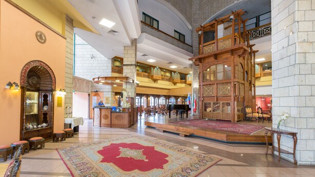 Un vestíbulo amplio con una imponente escalera, una zona de recepción y varias disposiciones de asientos.
