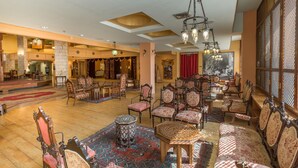Un vestíbulo amplio con muebles ornamentados, un candelabro imponente y un ventanal con vistas.