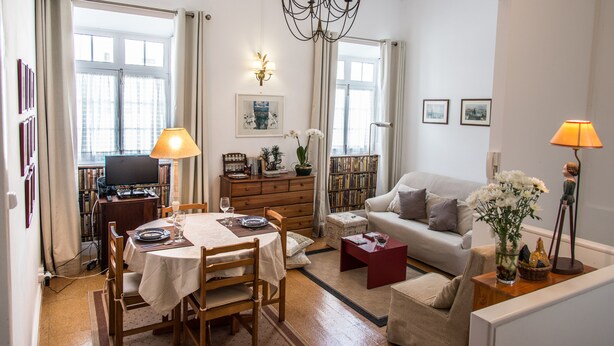 Ein helles Wohnzimmer mit Essbereich, einer Couch, einem Fernseher und einem Bücherregal.