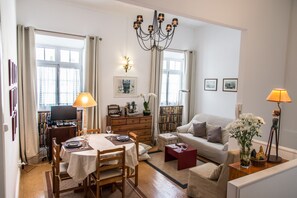 A well-lit living room with a dining area, a sofa, a TV, and a bookshelf. - Cozy Flat in City Center (Ponta Delgada)
