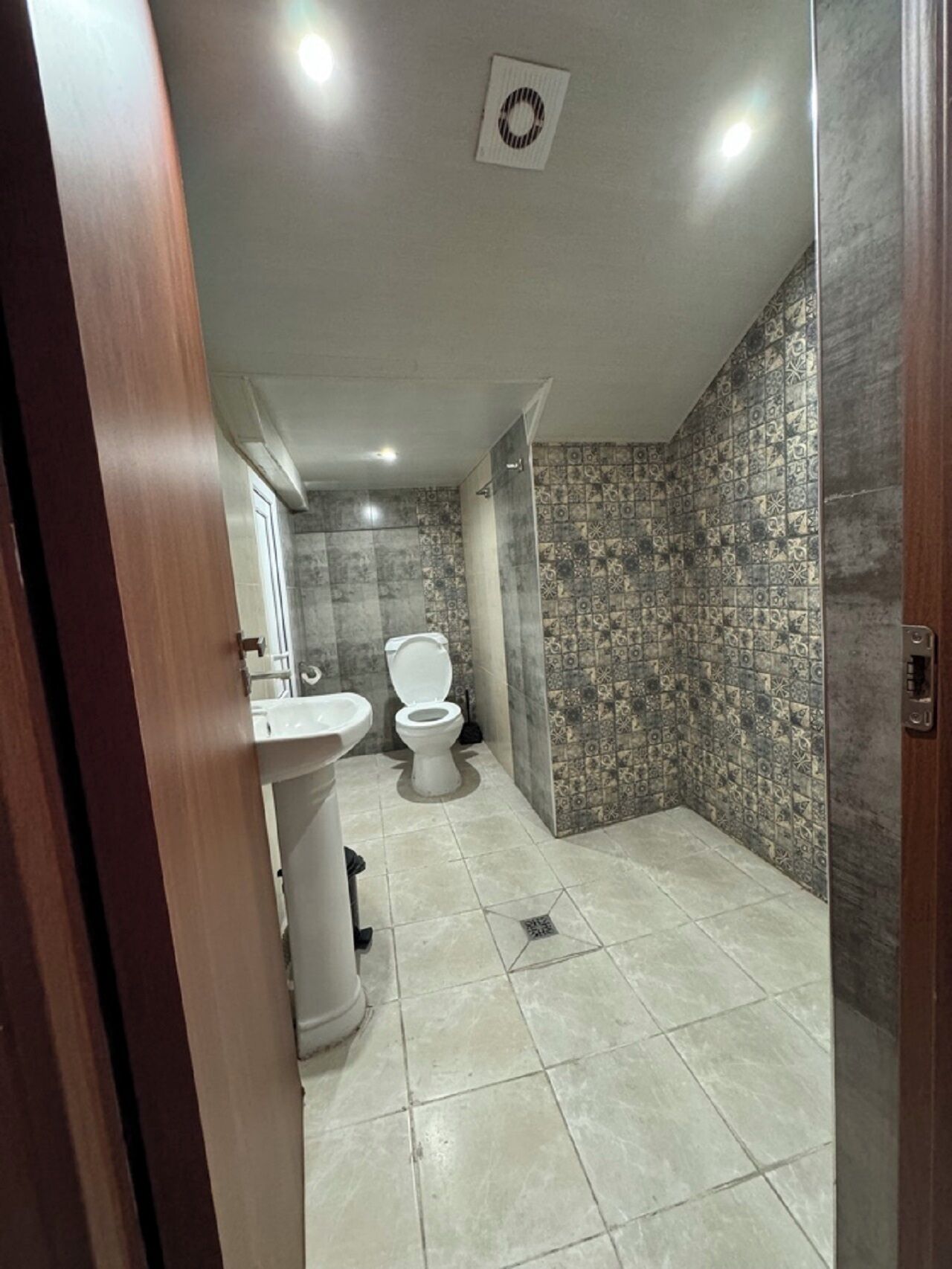 A bathroom with a toilet, sink, and shower area.