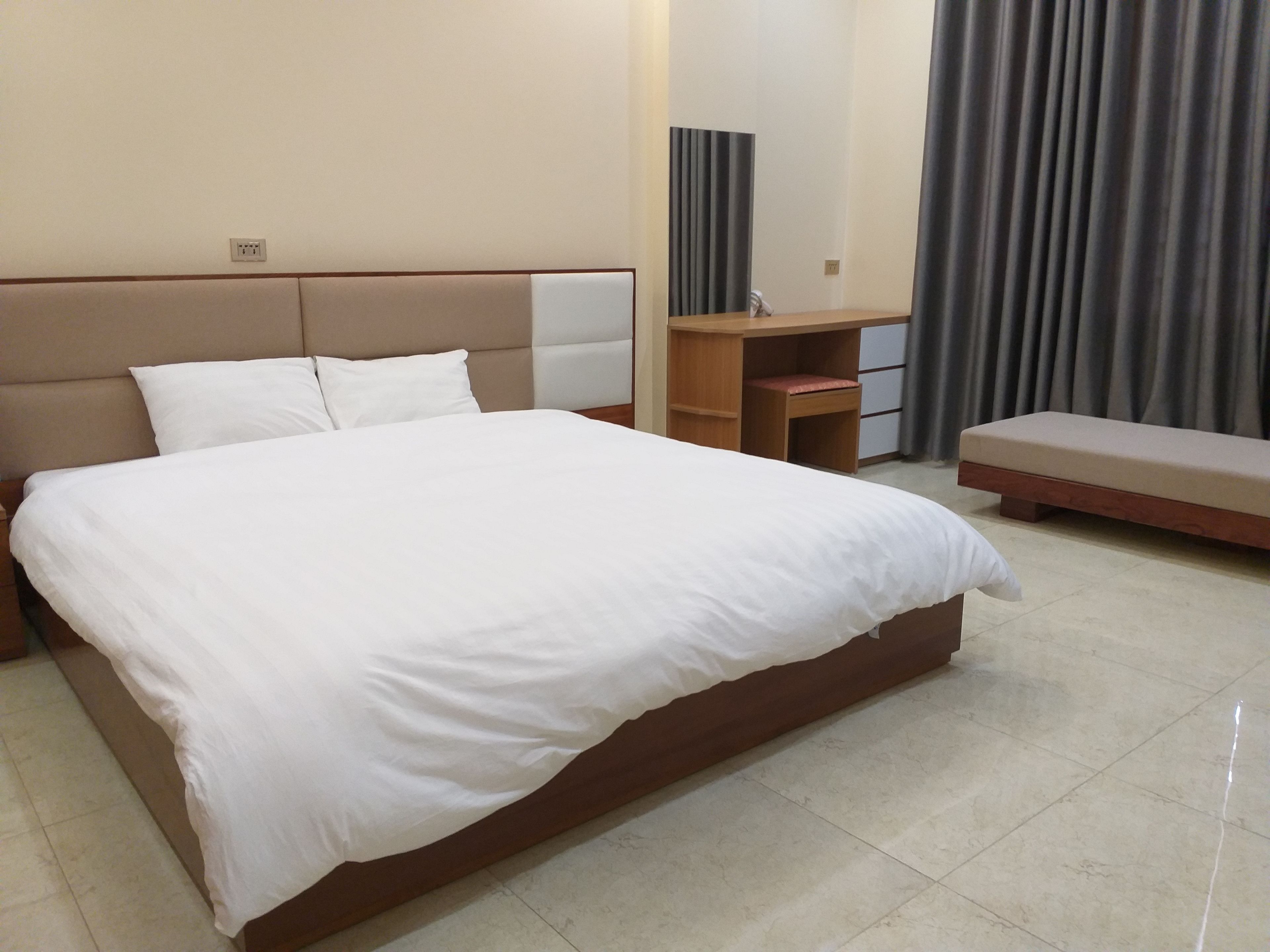 Ein Hotelzimmer mit einem großen Bett, einem Schreibtisch, einem Sessel und einer Bank.