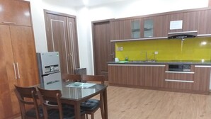 A compact kitchen with wooden cabinets, a built-in oven, and a small dining area with a glass table and chairs.