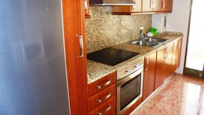 Eine Küche mit Holzausstattung, einer Edelstahl-Dunstabzugshaube, einer Granit-Arbeitsplatte, einer doppelten Spüle und einem eingebauten Backofen.