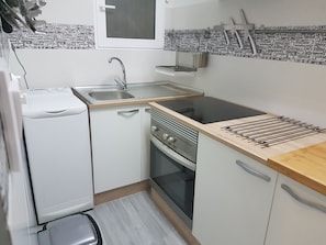 Een kleine keuken met een inbouwoven, een spoelbak en een kookplaat.