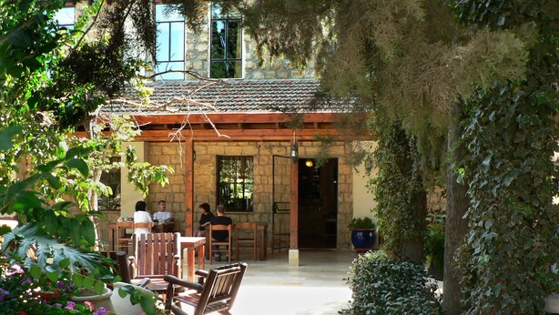 An outdoor patio area with stone walls, wooden furniture, and potted plants. - Beit Shalom Historical Boutique Hotel (Metula)