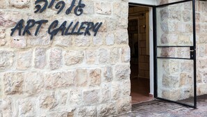 A stone wall with the words "1916 ART GALLERY" and an open glass door leading inside. - Beit Shalom Historical Boutique Hotel (Metula)