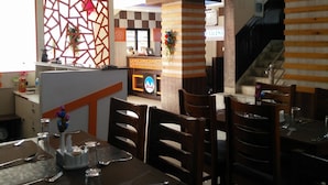 Un restaurant doté de plusieurs tables et chaises, d’un comptoir d’accueil et d’un escalier menant à un étage supérieur.