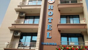 Un immeuble hôtelier à plusieurs étages, avec une enseigne « HÔTEL » bien visible, des balcons et des unités de climatisation.