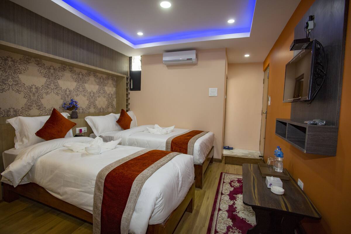A hotel room with two beds, a TV, a small table, and a mirror.