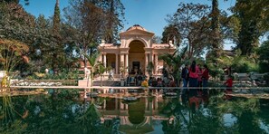 A large, ornate building with a central archway, surrounded by a reflective pool and lush greenery. - Hotel Marinha (Kathmandu)